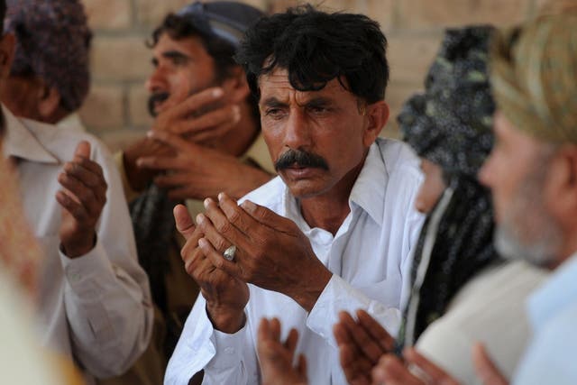 Pakistani resident Mohammad Iqbal (C) prays alongside relatives for his wife Farzana Parveen, who was beaten to death with bricks by her father and other family members 