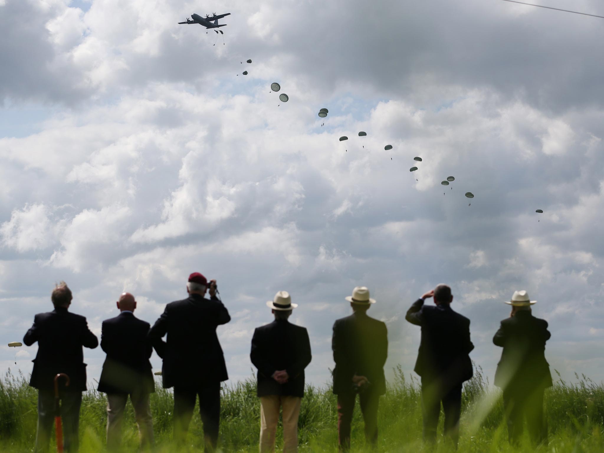 People watch as a parachute drop takes place near Ranville, France