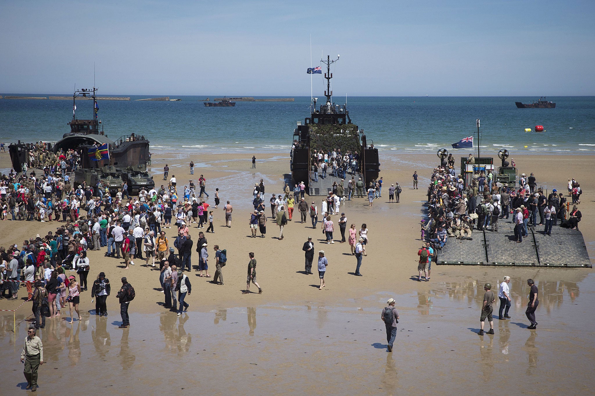 People visit Second World War landing crafts on the Arromanches beach, Normandy, on 6 June, 2014