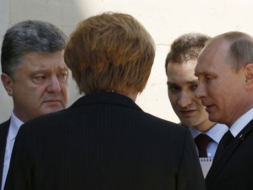 Putin and Poroshenko speak under the watchful eye of Angela Merkel during D-Day commemorations in Normandy.