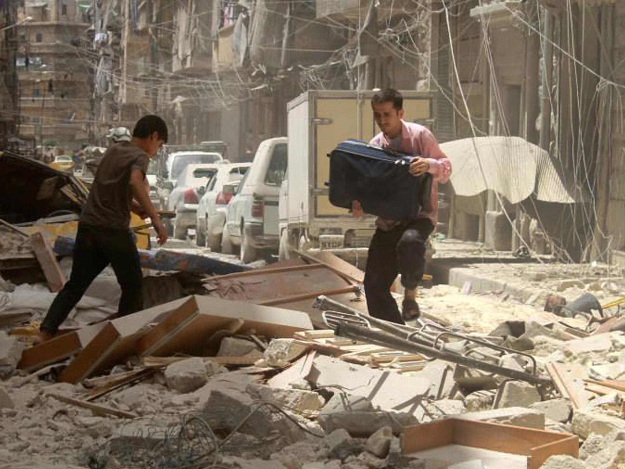 A man carries his bag as he walks on the debris of a damaged building which was attacked by a government forces airstrike, in Aleppo, Syria