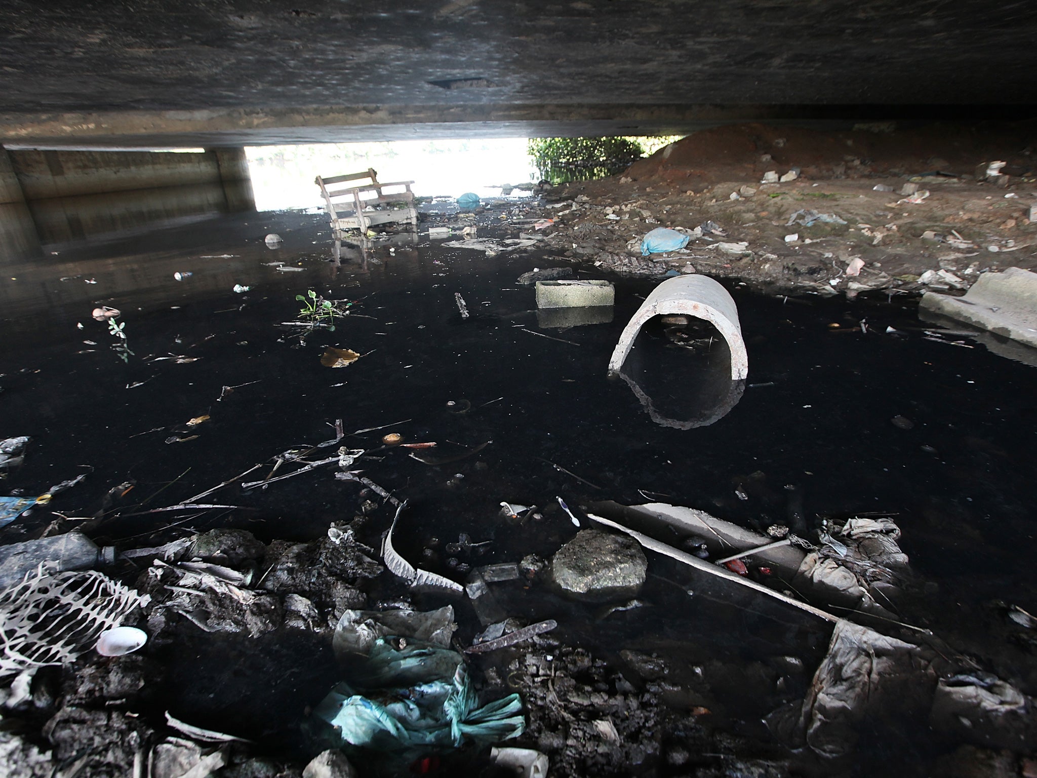 A polluted tributary of Guanabara Bay is shown littered with garbage near Rio de Janeiro. Source: Getty Images