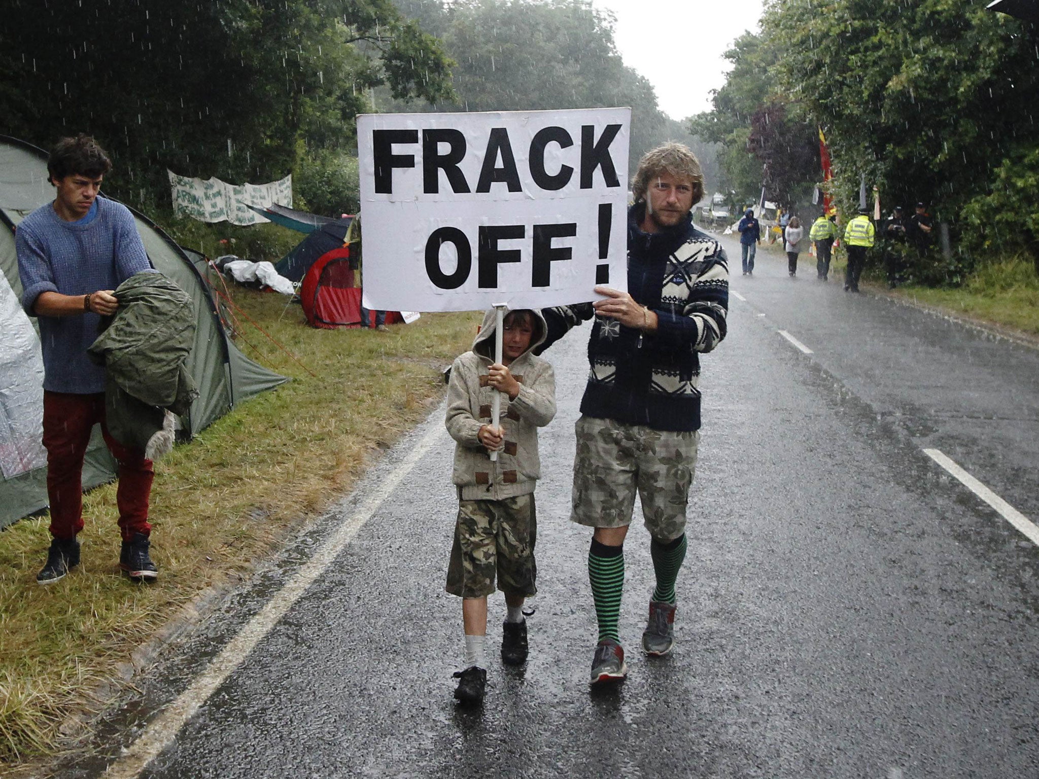 A man and boy walk through the rain with a placard during an anti-fracking protest