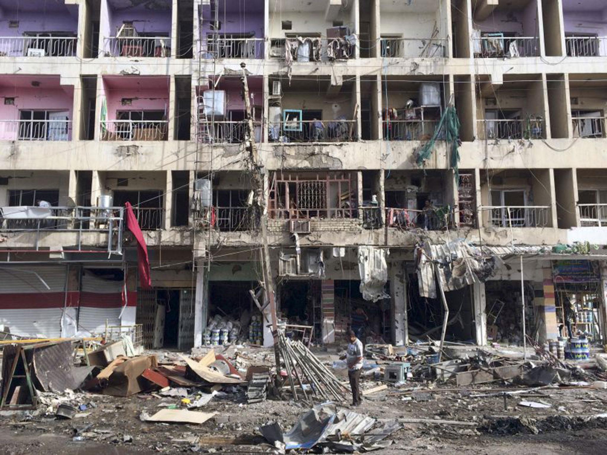 Iraqi civilians inspect the aftermath of a car bombing in south-east Baghdad in Iraq yesterday