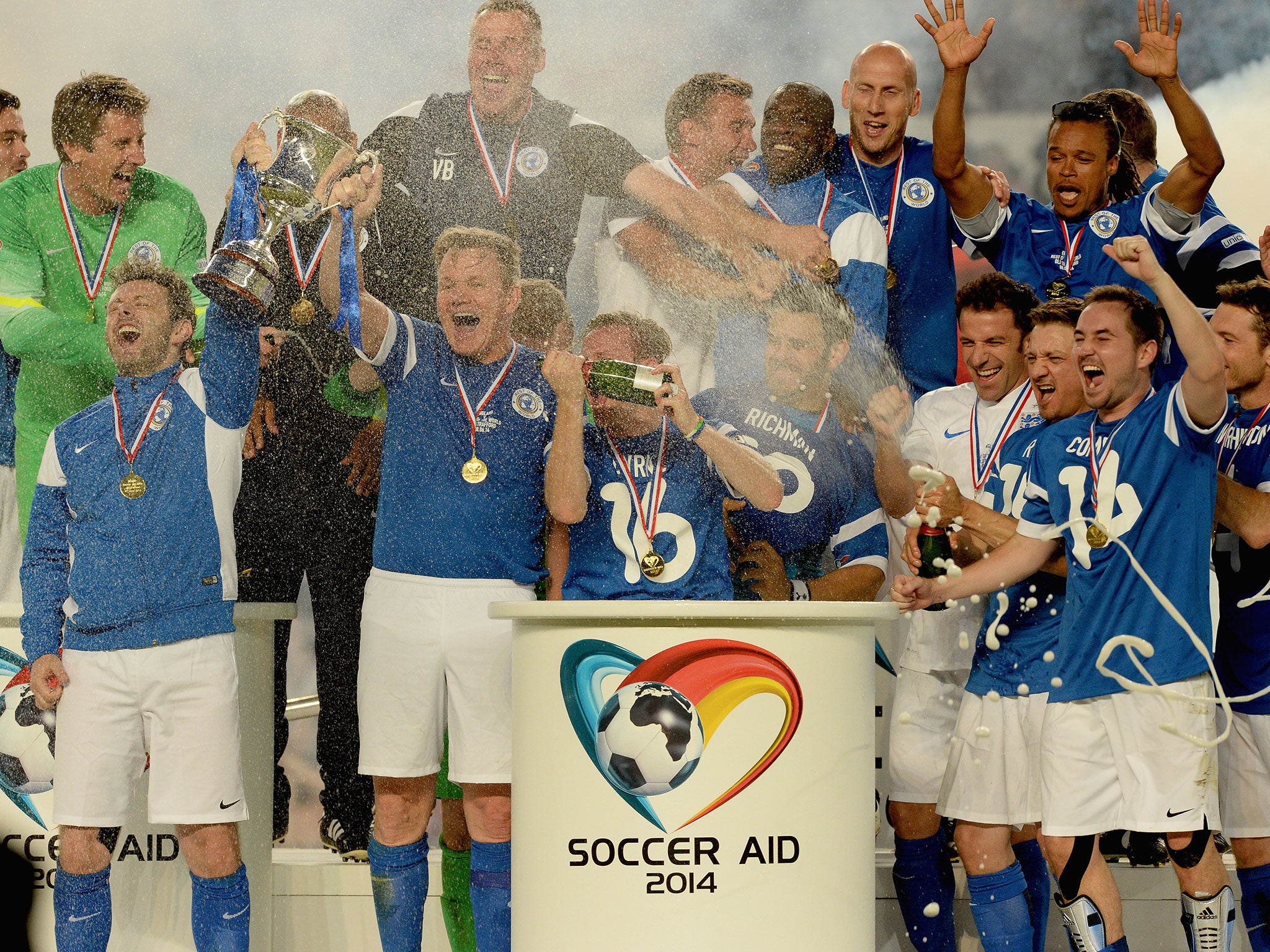 Michael Sheen and Gordon Ramsay of the Rest of the World lift the trophy as they celebrate with team mates victory in the Soccer Aid 2014 match at Old Trafford