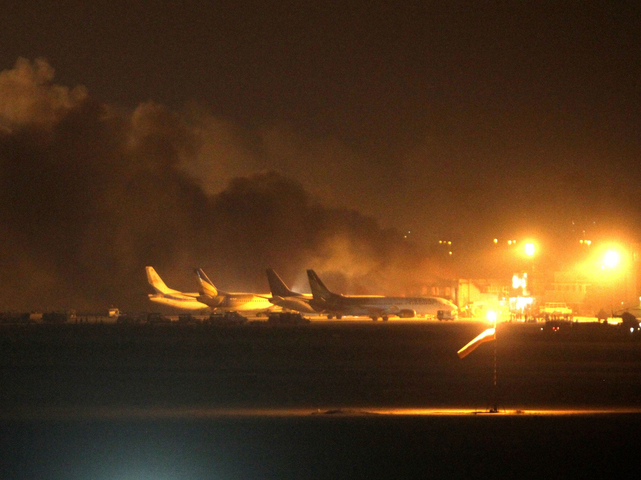 Fire illuminates the sky above Karachi airport terminal where security forces are fighting with attackers