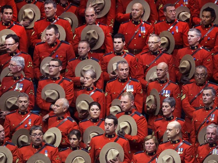 RCMP officers stand in silence during the regimental funeral of three slain officers at the Moncton Coliseum on Tuesday, June 10, 2014, in Moncton, New Brunswick, Canada. Thousands of police officers from across Canada attended the funeral for Fabrice Gevaudan, Douglas Larche and Dave Ross, the three Mounties killed by a gunman on June 4, 2014.