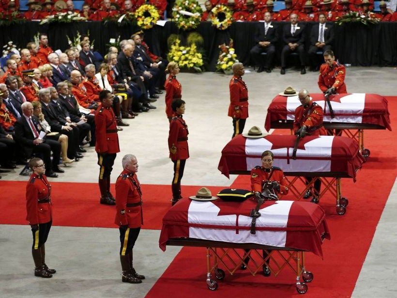 Royal Canadian Mounted Police officers collect possessions from the caskets of three fellow officers who were killed last week during a regimental funeral in Moncton, New Brunswick, June 10, 2014.