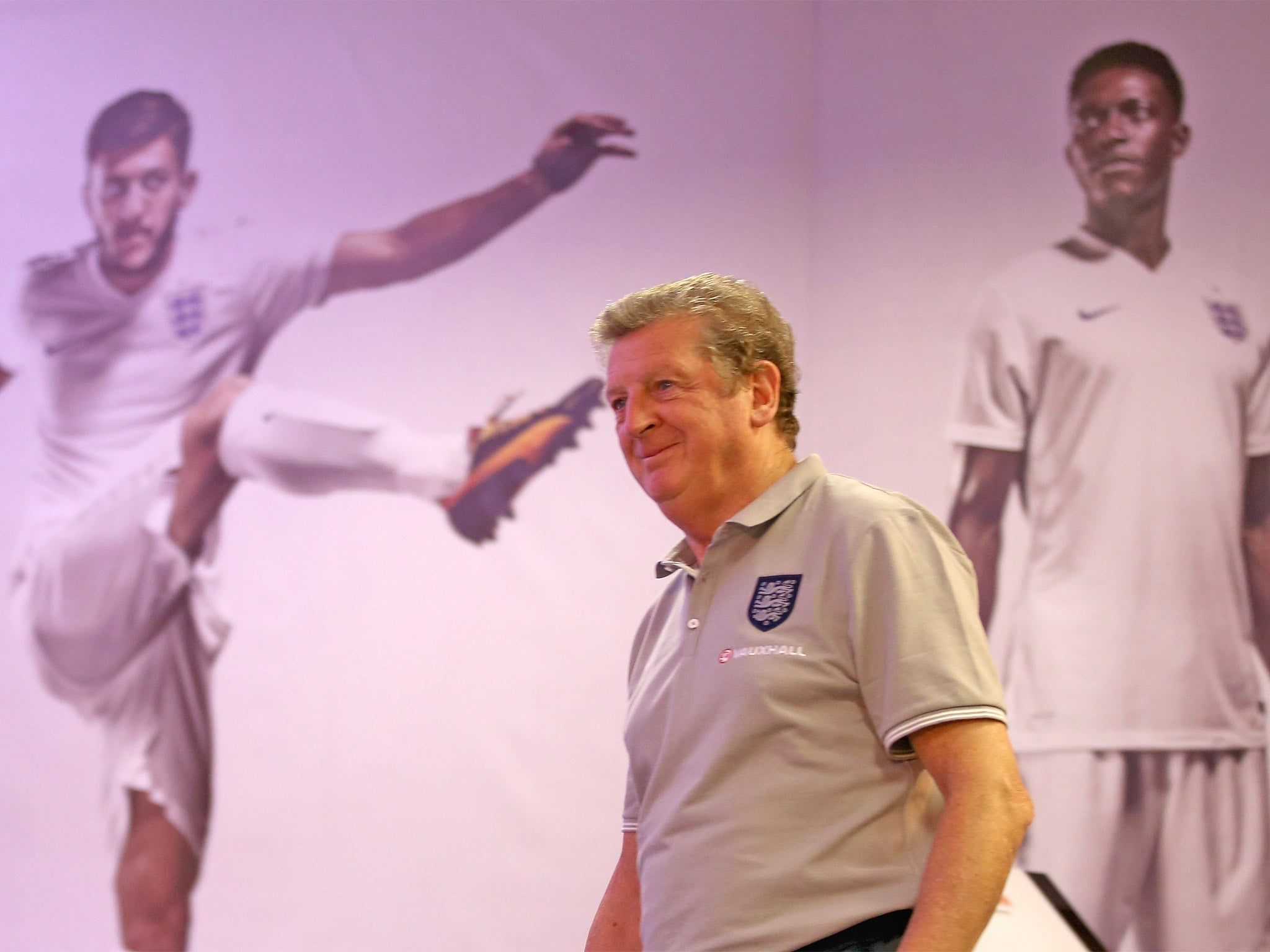 The England manager, Roy Hodgson, walks into his press conference past images of his squad members Adam Lallana and Danny Welbeck in Rio de Janeiro
