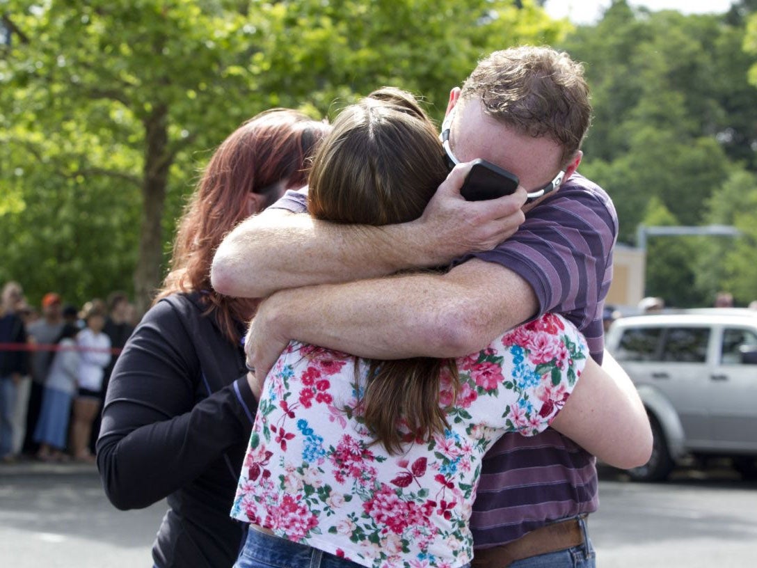 A family embraces after students arrived at a shopping center parking lot in Wood Village, Ore., after a shooting at Reynolds High School Tuesday, June 10, 2014, in nearby Troutdale. A gunman killed a student at the high school east of Portland Tuesday an