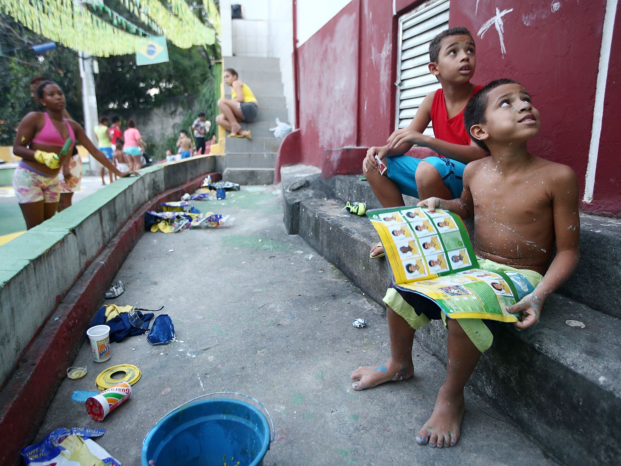 Brazilians gather while painting a section of the Santa Marta shantytown, or 'favela', in Brazilian colors as a boy holds his Panini World Cup stickers book