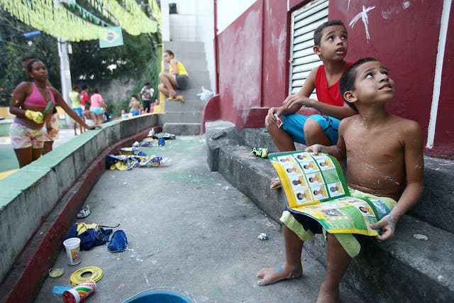 Brazilians gather while painting a section of the Santa Marta shantytown, or 'favela', in Brazilian colors as a boy holds his Panini World Cup stickers book