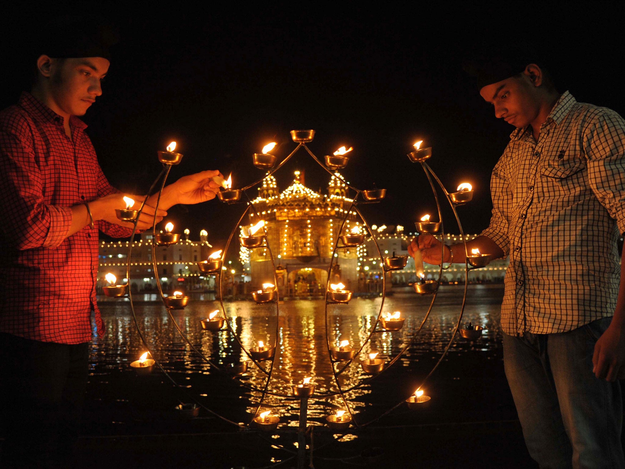 Indian Sikh devotees pose as they light lamps at the Golden Temple in Amritsar