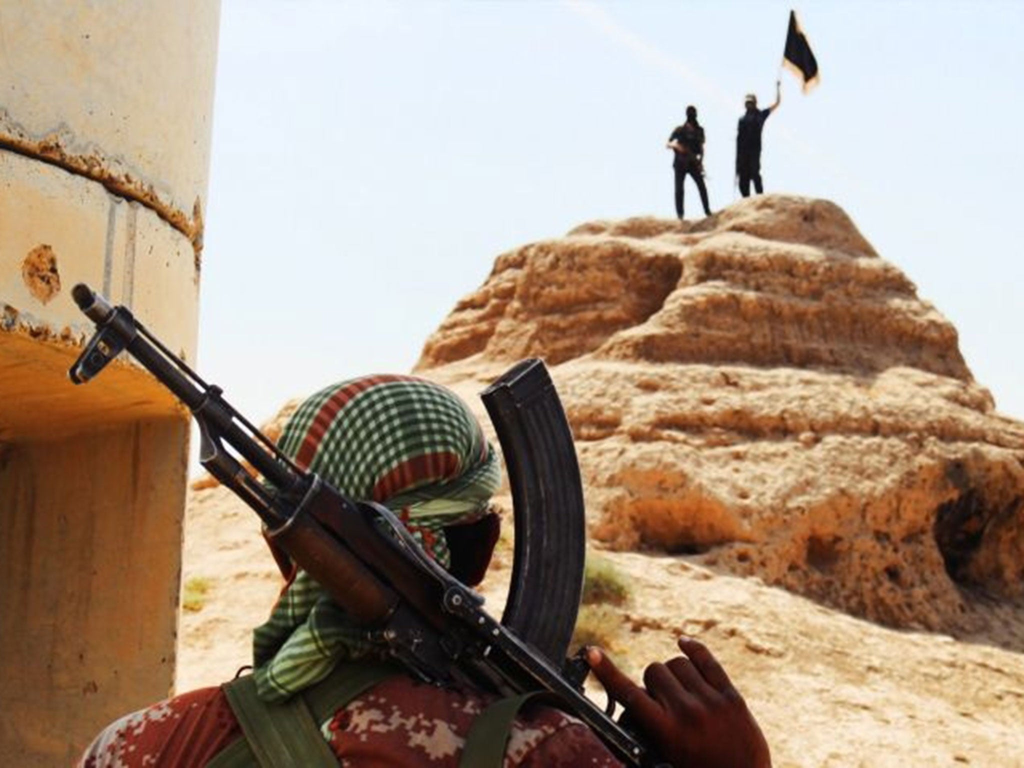 Isis militants waving an Islamist flag after the seizure of an Iraqi army checkpoint in Salahuddin