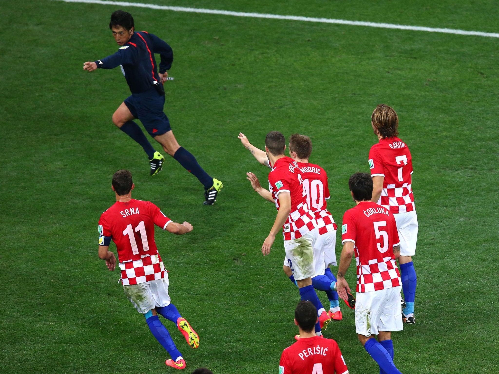 Croatian players chase Yuichi Nushima after he awards Brazil a controversial penalty