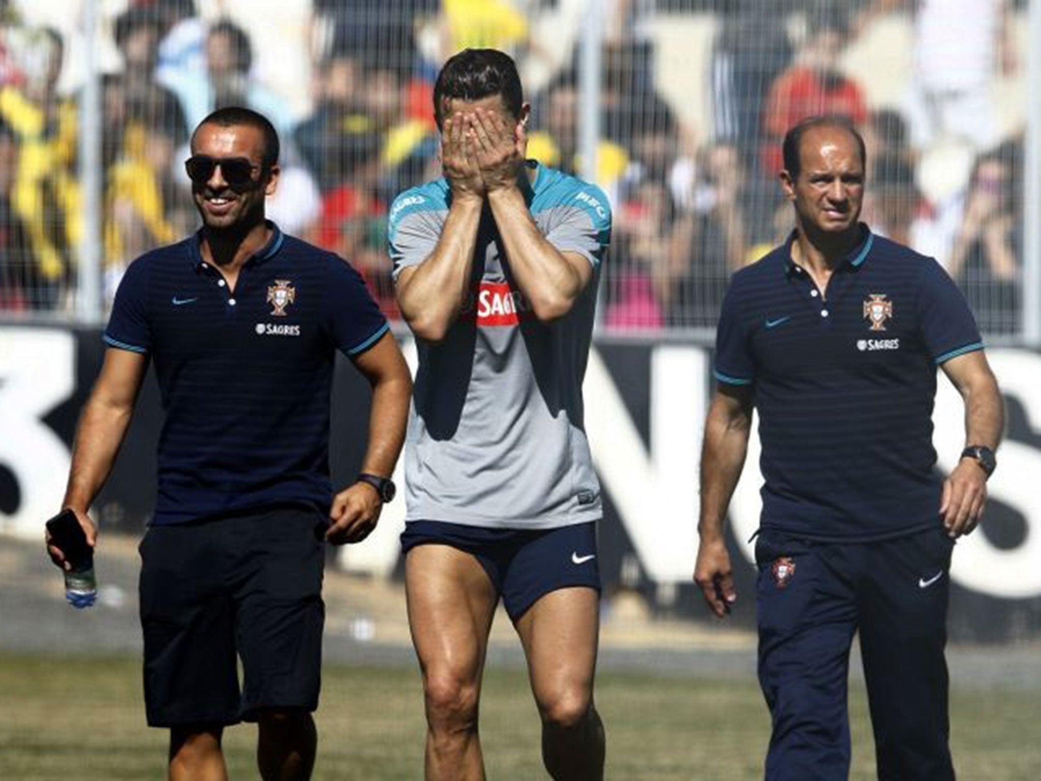 Cristiano Ronaldo covers his face as he limps out of a Portugal training session