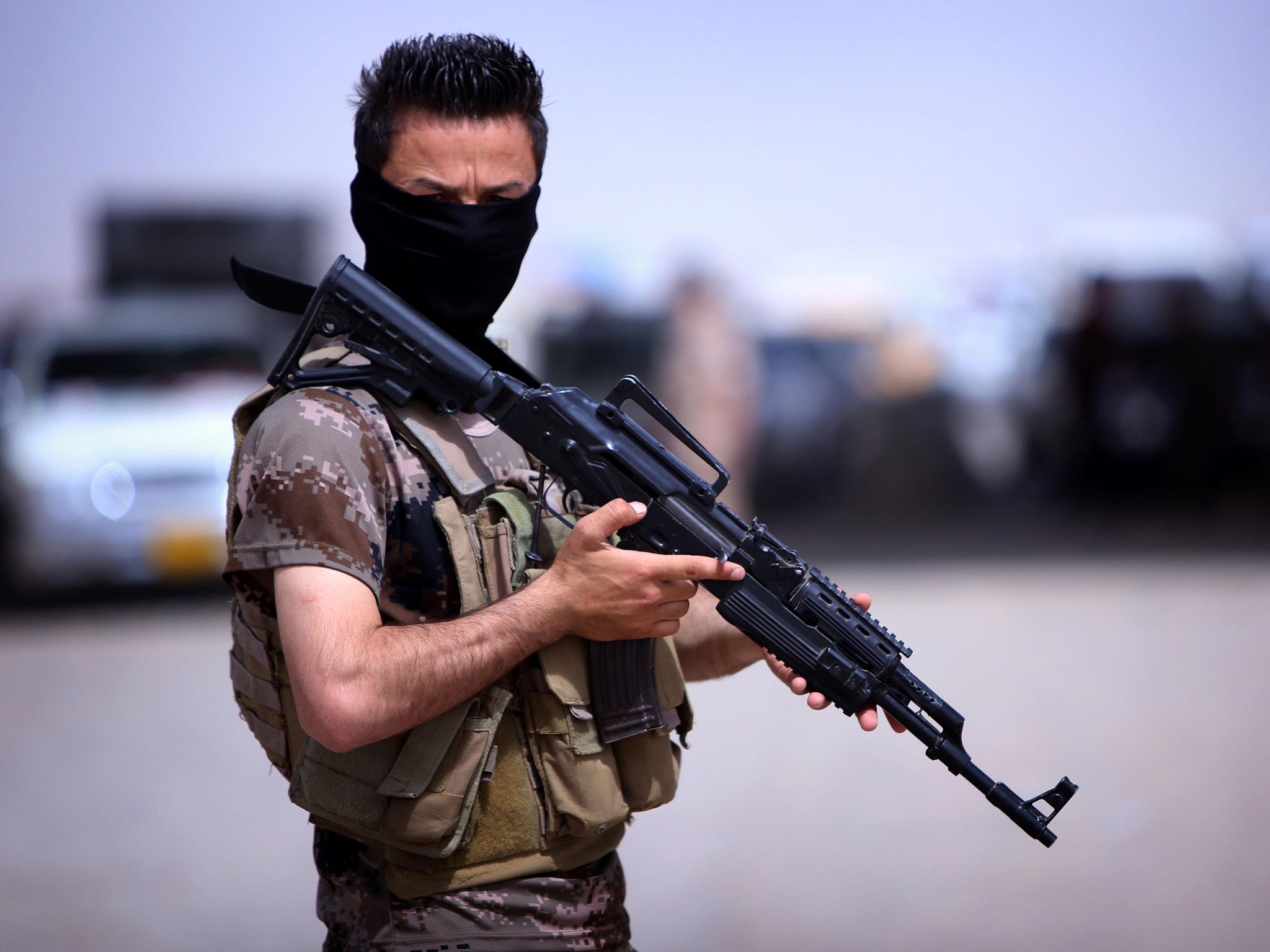 A masked Pershmerga fighter from Iraq's autonomous Kurdish region guards a temporary camp set up to shelter Iraqis fleeing violence in the northern Nineveh province, in Aski kalak