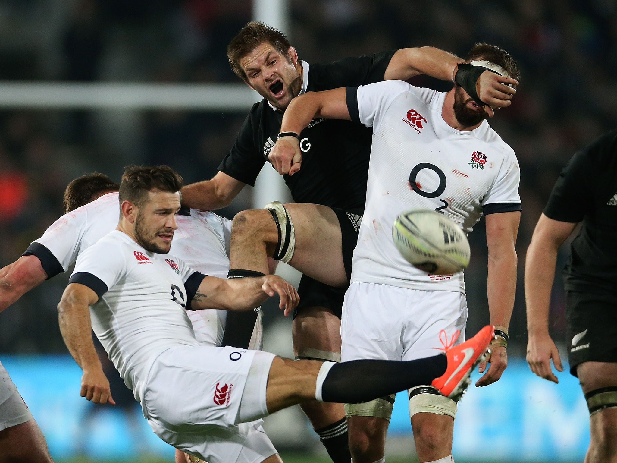 Danny Care kicks the ball as Richie McCaw attempts to push past Tom Wood