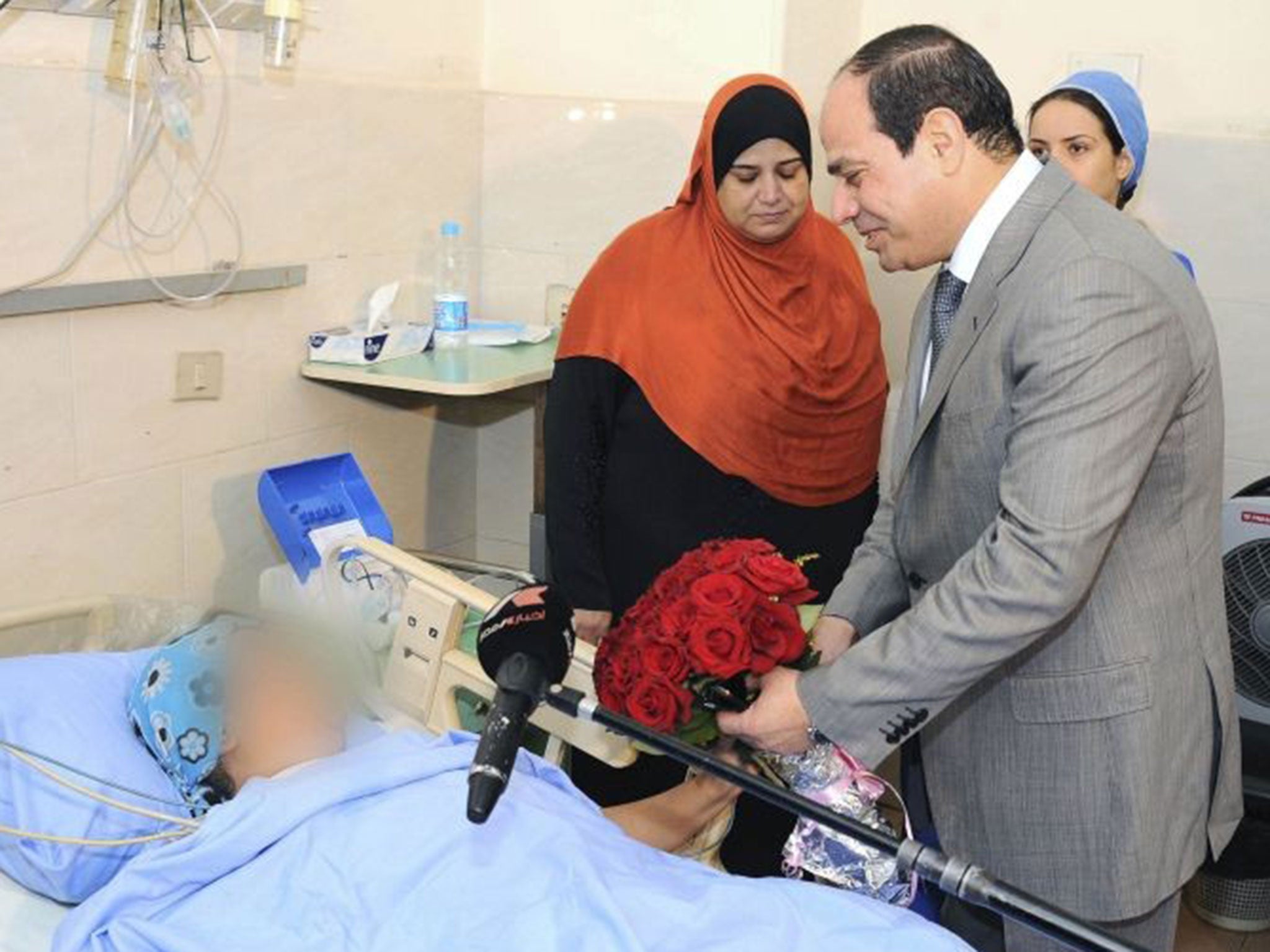 Egypt's President Abdel Fattah al-Sisi presents a bouquet of flowers to a woman who was sexually assaulted by a mob during Sunday's celebrations marking his inauguration, at a hospital in Cairo June 11, 2014