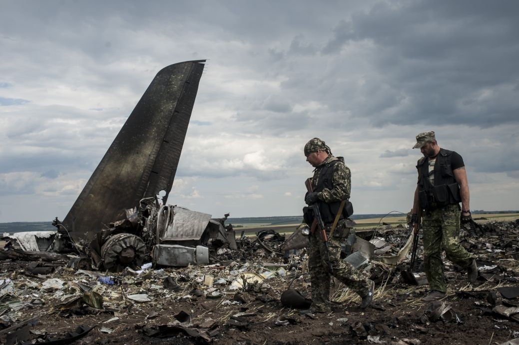 Pro-Russian fighters walk passed the site of remnants of a downed Ukrainian army aircraft Il-76 at the airport near Luhansk, Ukraine
