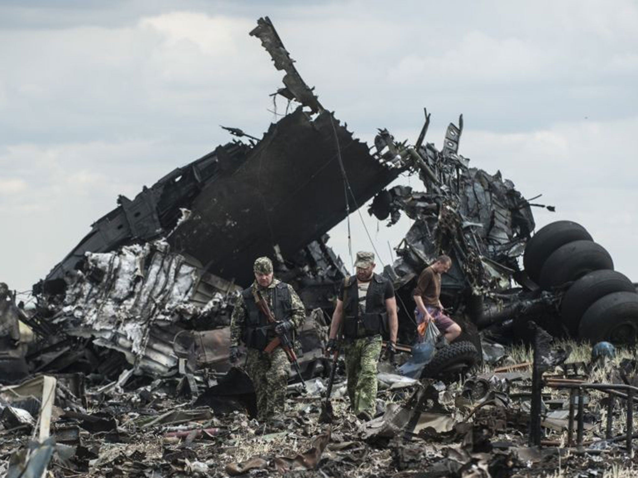 Pro-Russian fighters walk passed the site of remnants of a downed Ukrainian army aircraft Il-76 at the airport near Luhansk, Ukraine