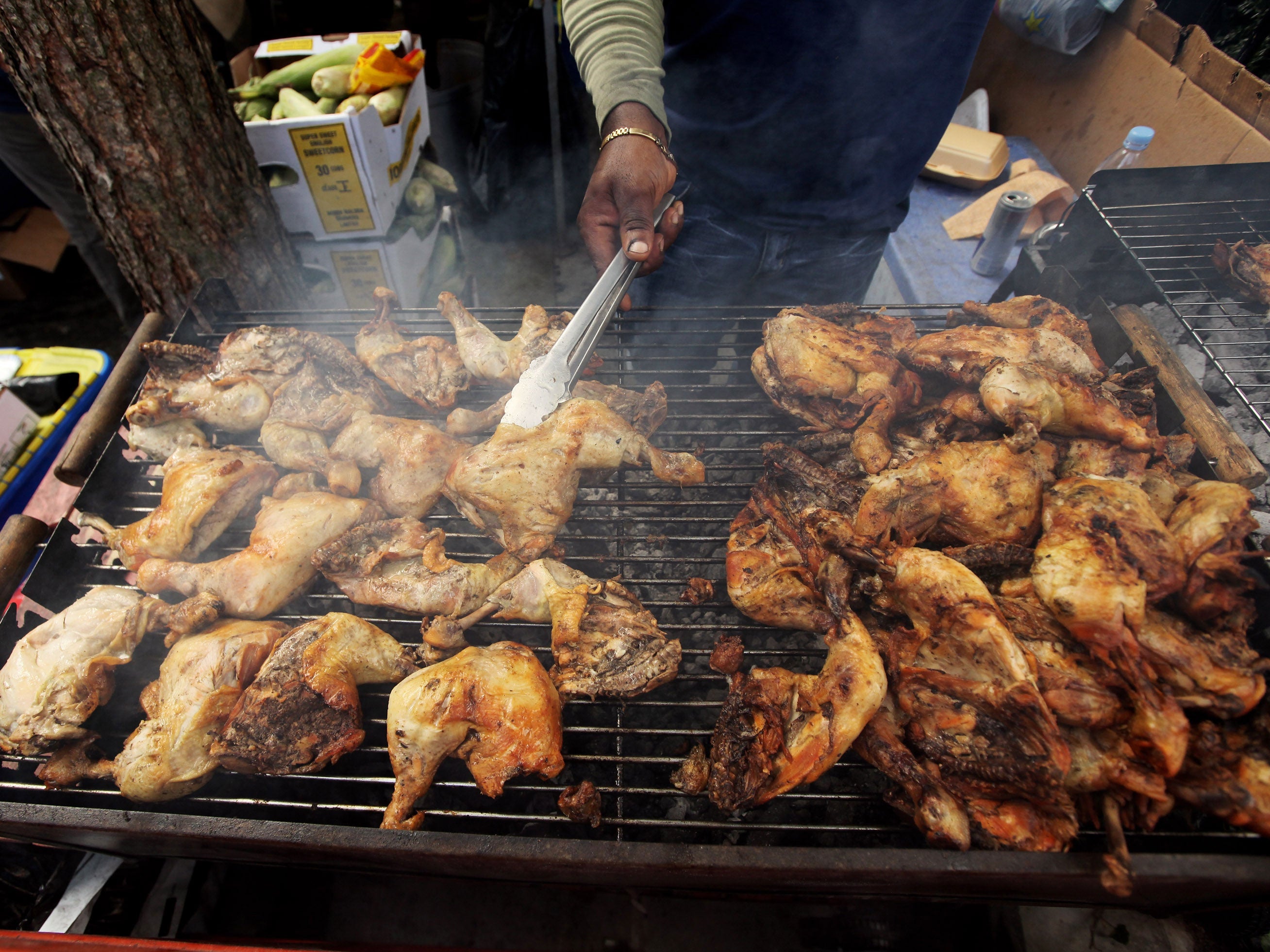 A street trader cooks chicken on a barbecue at Notting Hill Carnival