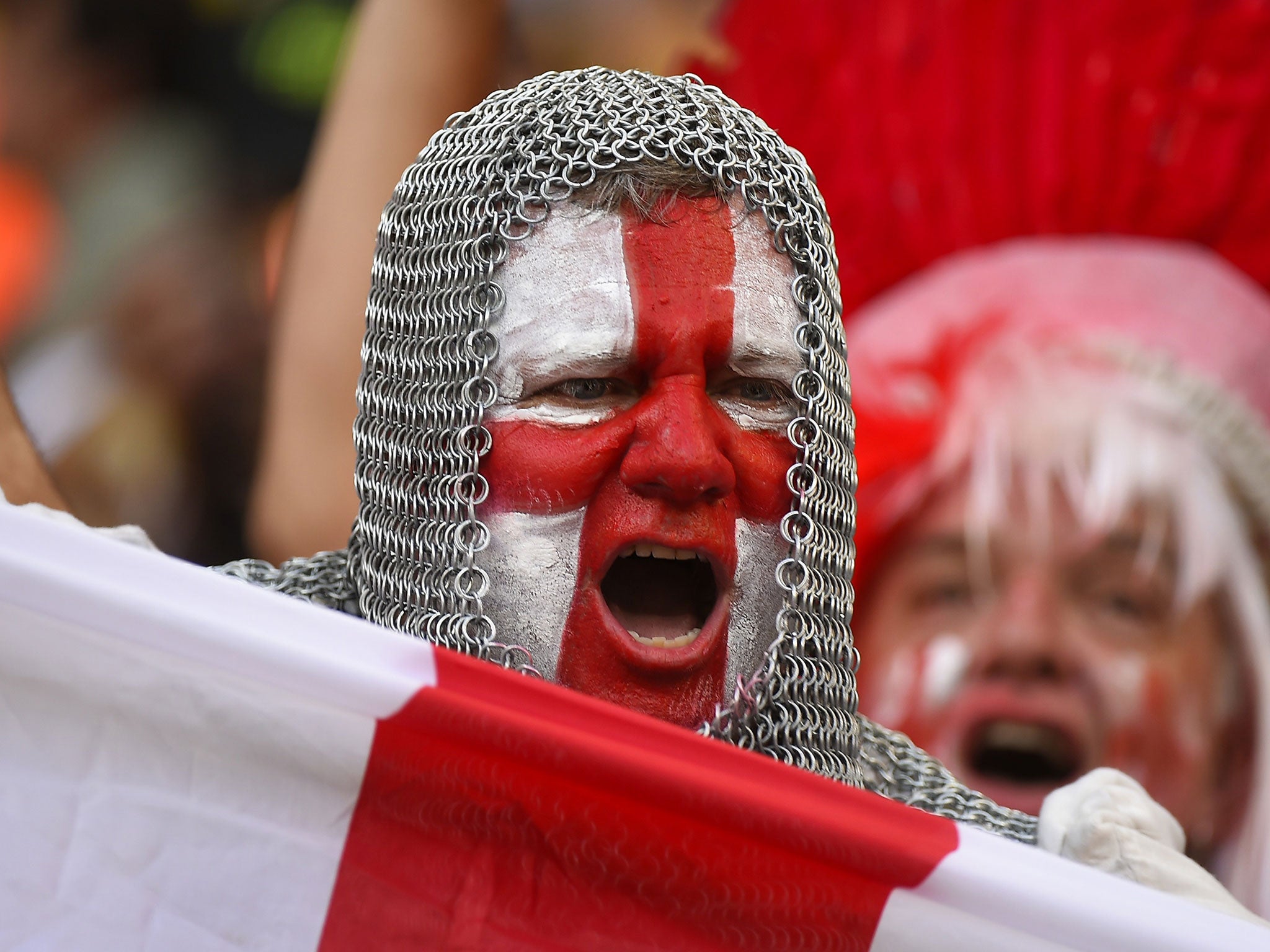 An England fan with his face painted in the colours of his national flag and wearing a chain mail costume cheers prior to a football match between England and Italy