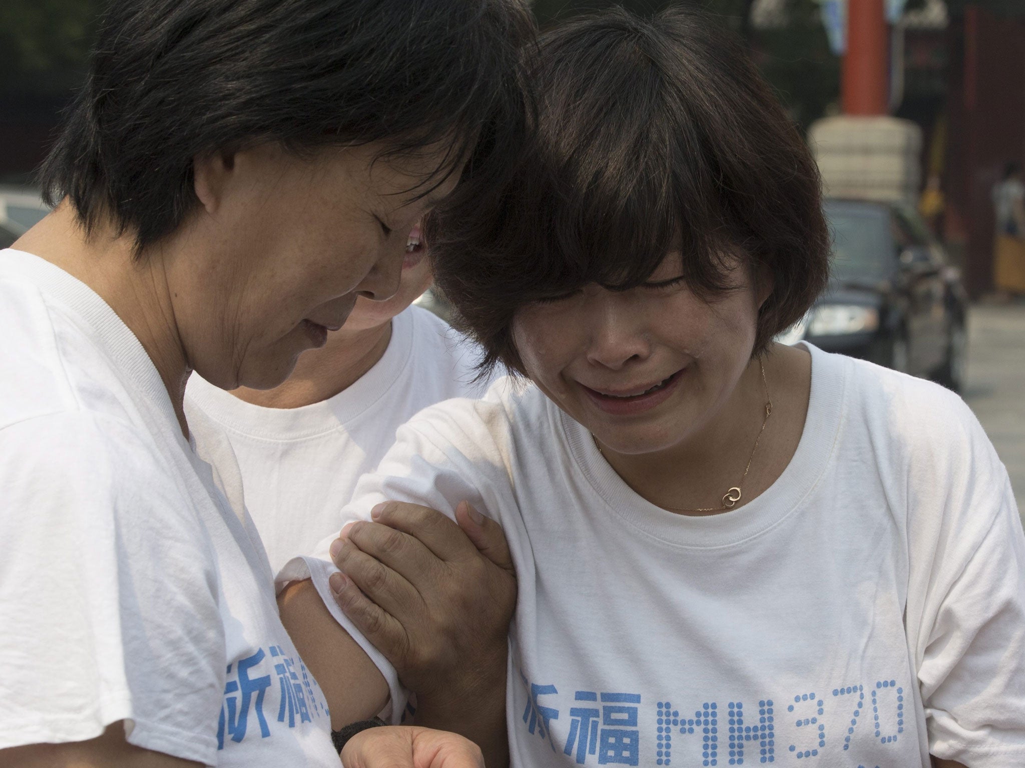 Chinese relatives of passengers of Malaysia Airlines flight MH370 console each other before entering the Lama Temple to pray in Beijing, China, 15 June 2014