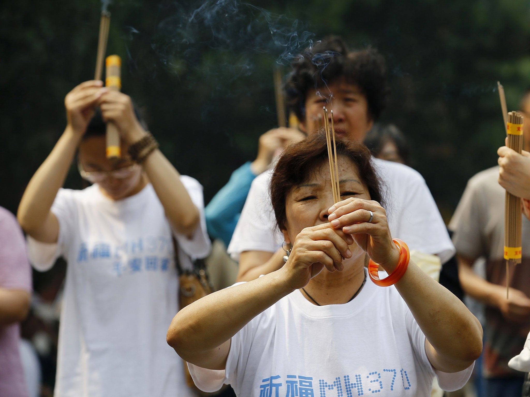 Family members of passengers aboard the missing Malaysia Airlines flight MH370 burn incense to pray at Yonghegong Lama Temple in Beijing