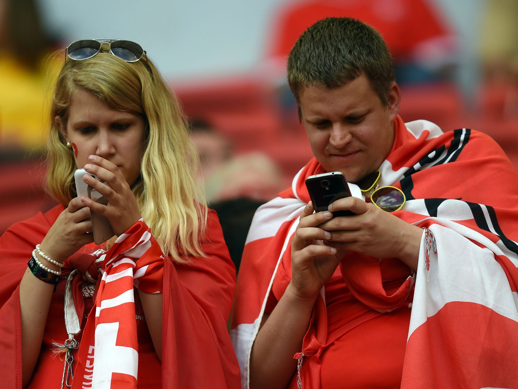 Swiss fans check the smartphones prior to the match between Switzerland and Ecuador in Brasilia during the 2014 World Cup on June 15, 2014.