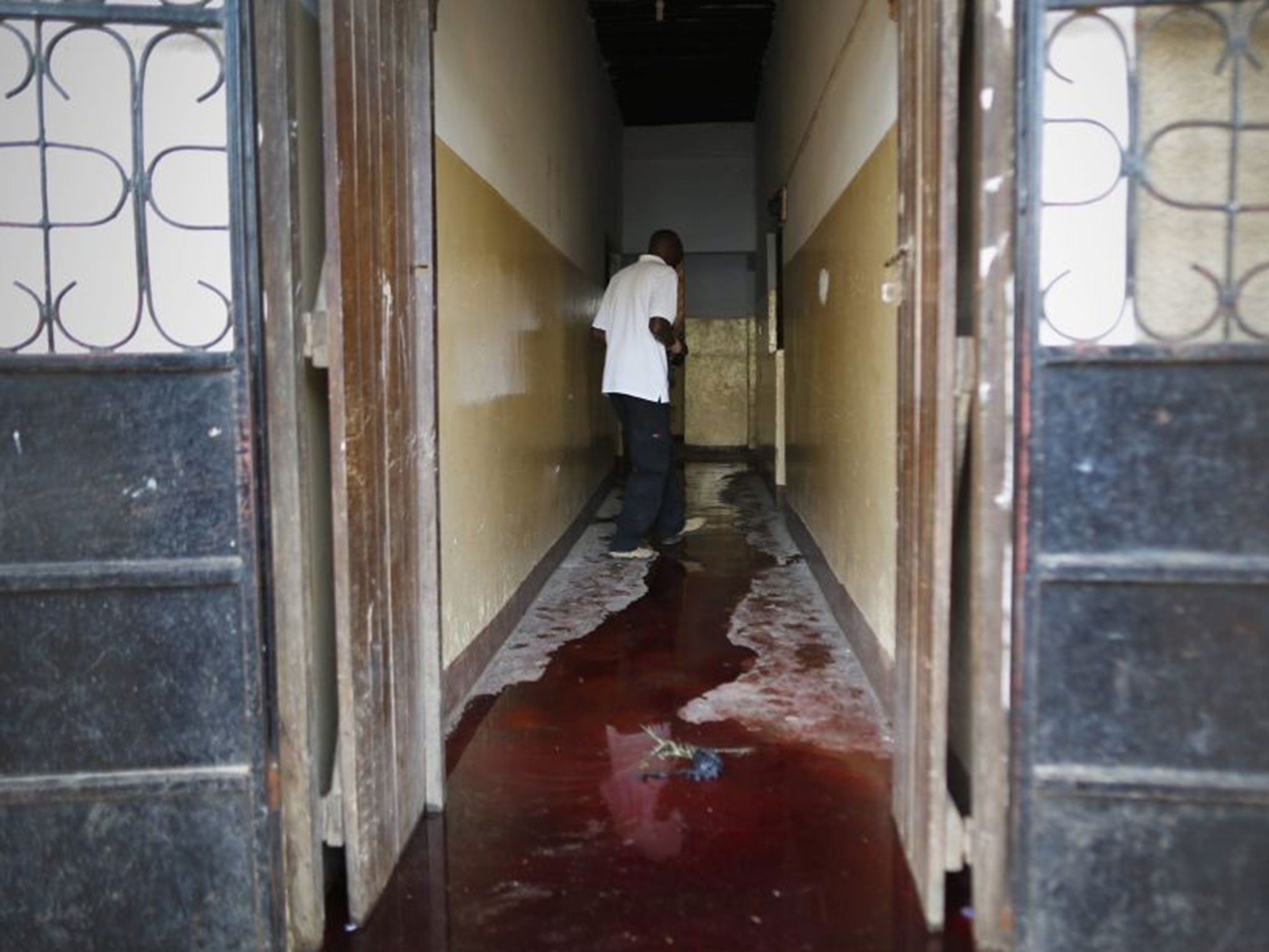 A man walks near a pool of blood at an entrance of a building in the small coastal town of Mpeketoni near Lamu, Kenya, 16 June 2014.