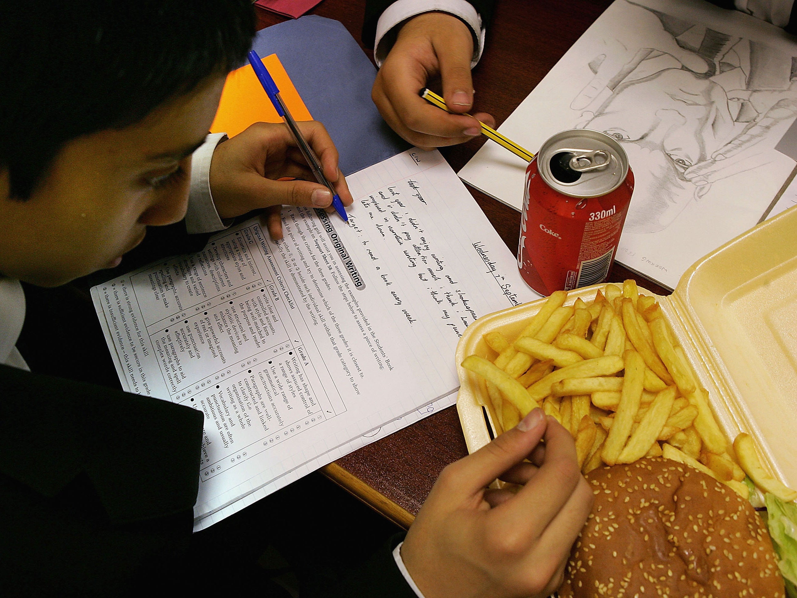 A school student eats a hamburger and chips as part of his lunch (Getty Images)