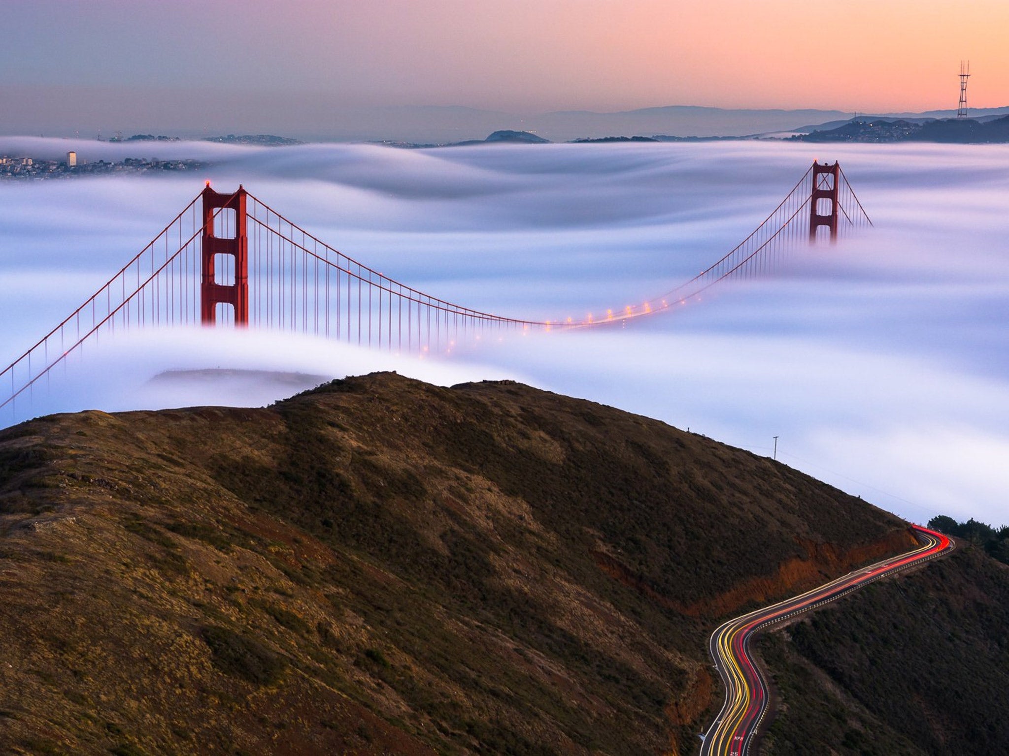 A Love Mysterious: The sun sets as the majestic fog of the Pacific coast glides under the iconic Golden Gate Bridge. The long exposure of the fog reveals a silky texture as the low clouds rise and fall over San Francisco's trademark hills. All the while,