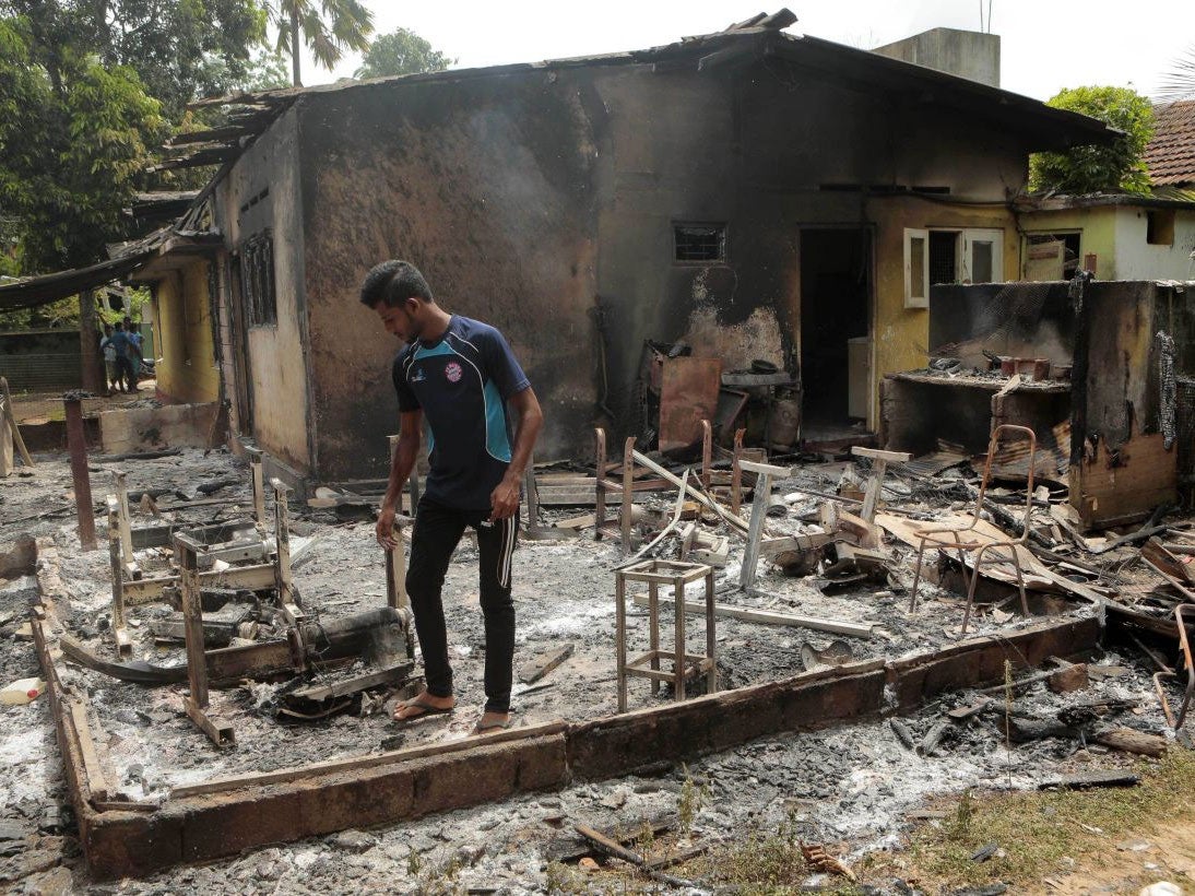 A Sri Lankan Muslim man inspects the charred remains of a bag tailoring unit following attacks by hard-line Buddhist group Bodu Bala Sena in Aluthgama