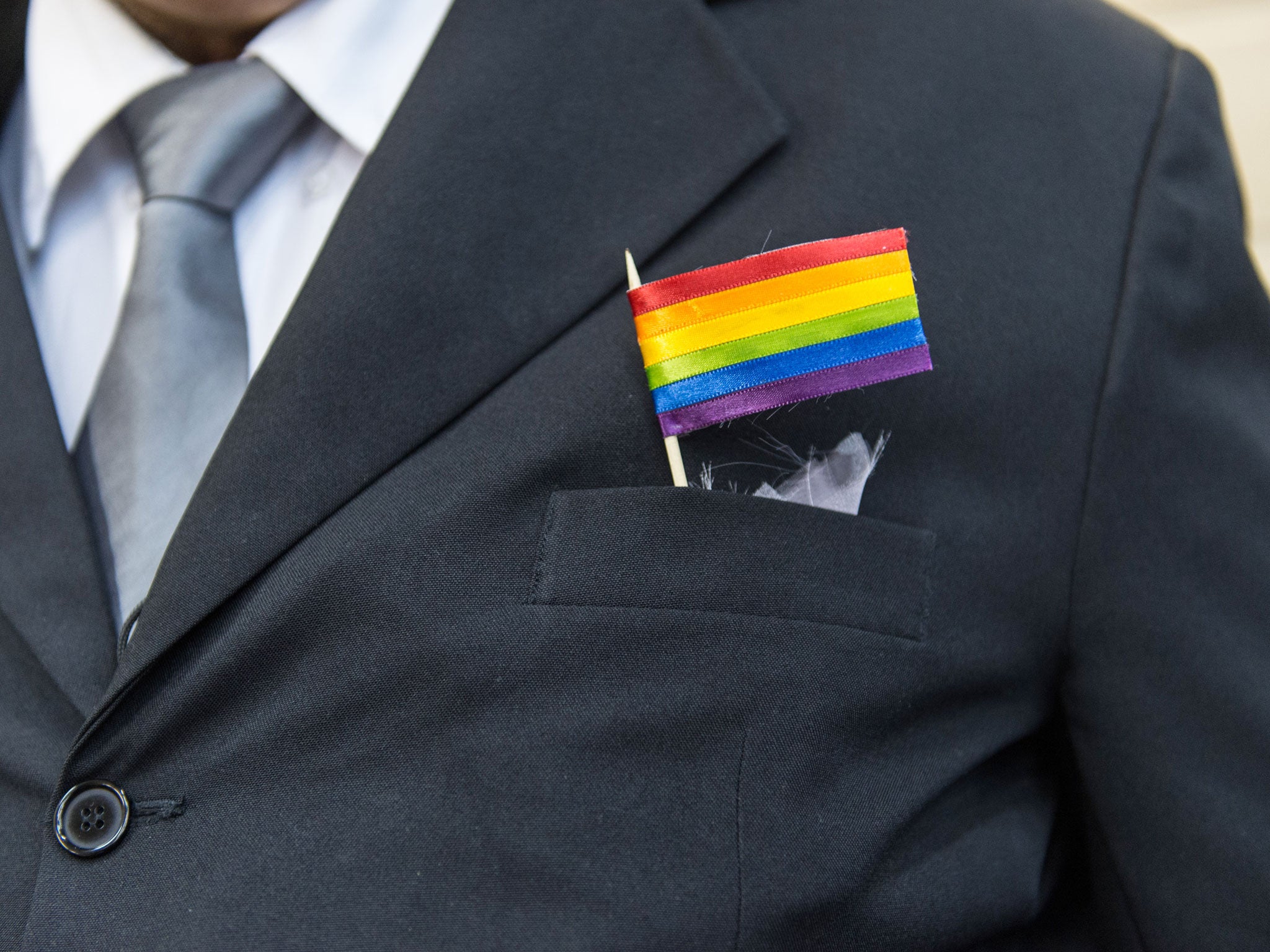 The father of a bride wears a rainbow flag during the wedding ceremony at the Court of Justice of the State of Rio de Janeiro in Rio de Janeiro, Brazil, on December 8, 2013. 130 gay couples are getting married in the first massive wedding ceremony since t