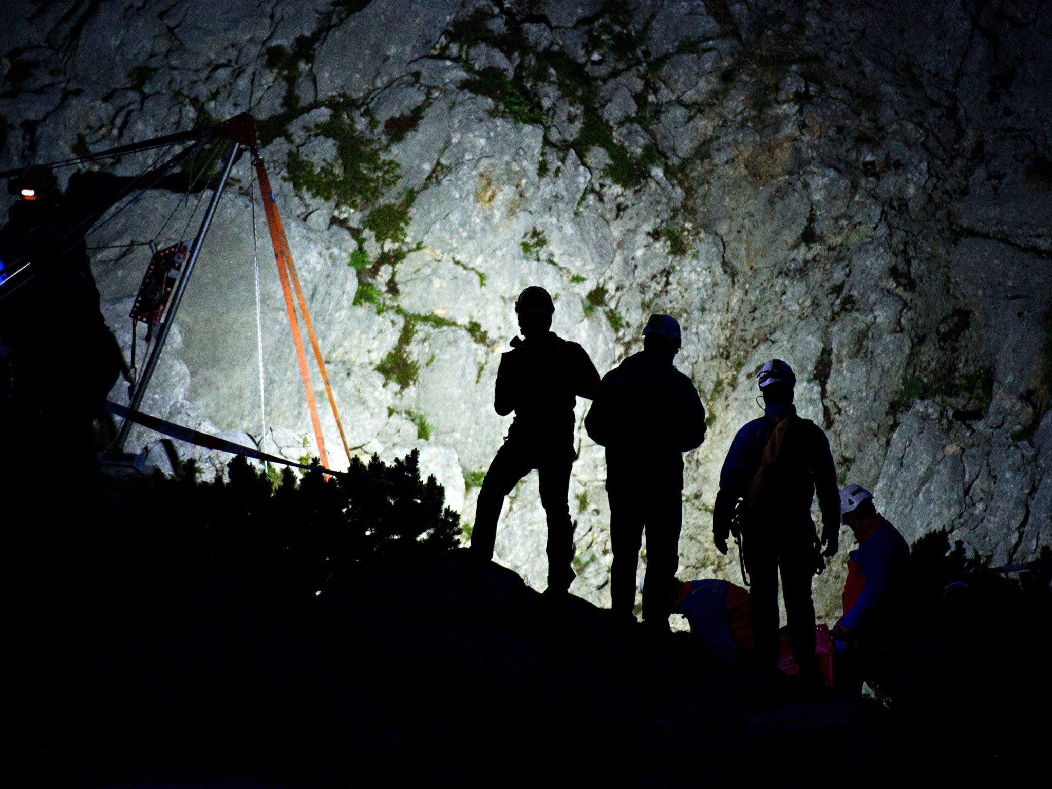 Rescue helpers wait for their deployment near a cable winch at the mouth of the 'Riesending' cave at the Untersberg mountain near Marktschellenberg, Germany