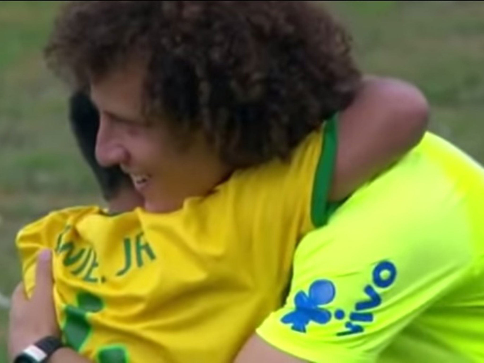 David Luiz embraces an eight-year-old Brazil fan after he ran on to the pitch at a training session