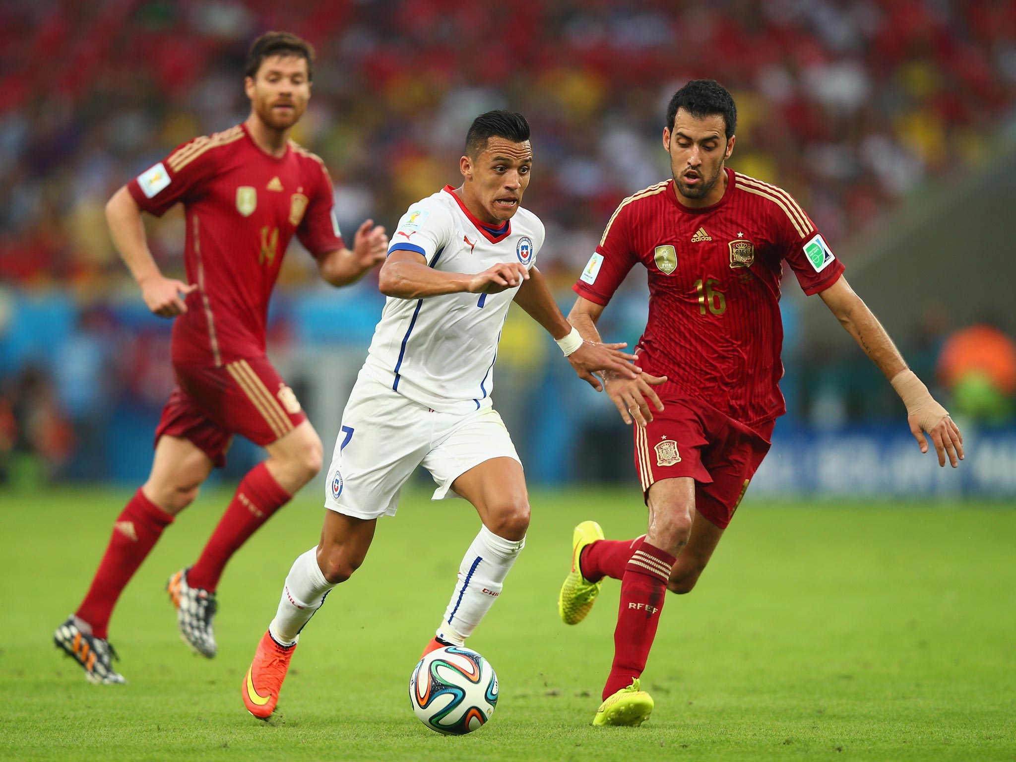 Chile’s Alexis Sanchez steers the ball past Sergio Busquets during the victory over Spain