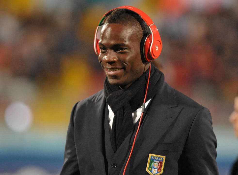 Italy's Mario Balotelli listens to music as he walks on the field before a match
