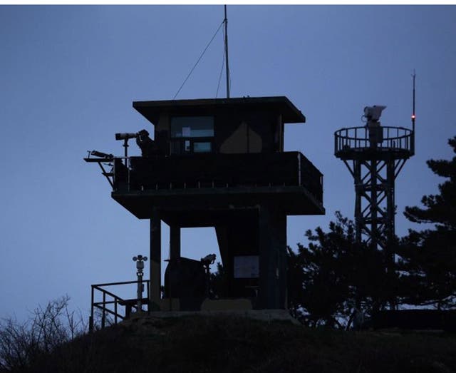 A South Korean soldier (unlinked to the shooting) uses binoculars to look out to sea from a watchtower on the Yeonpyeong island, which lies just inside the South Korean side of the Northern Limit Line (NLL) in the Yellow Sea 