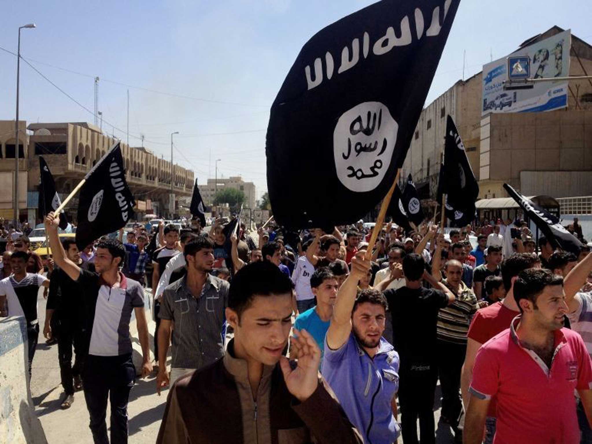 Rally point: Isis supporters wave al‑Qa’ida flags outside the provincial government HQ in Mosul