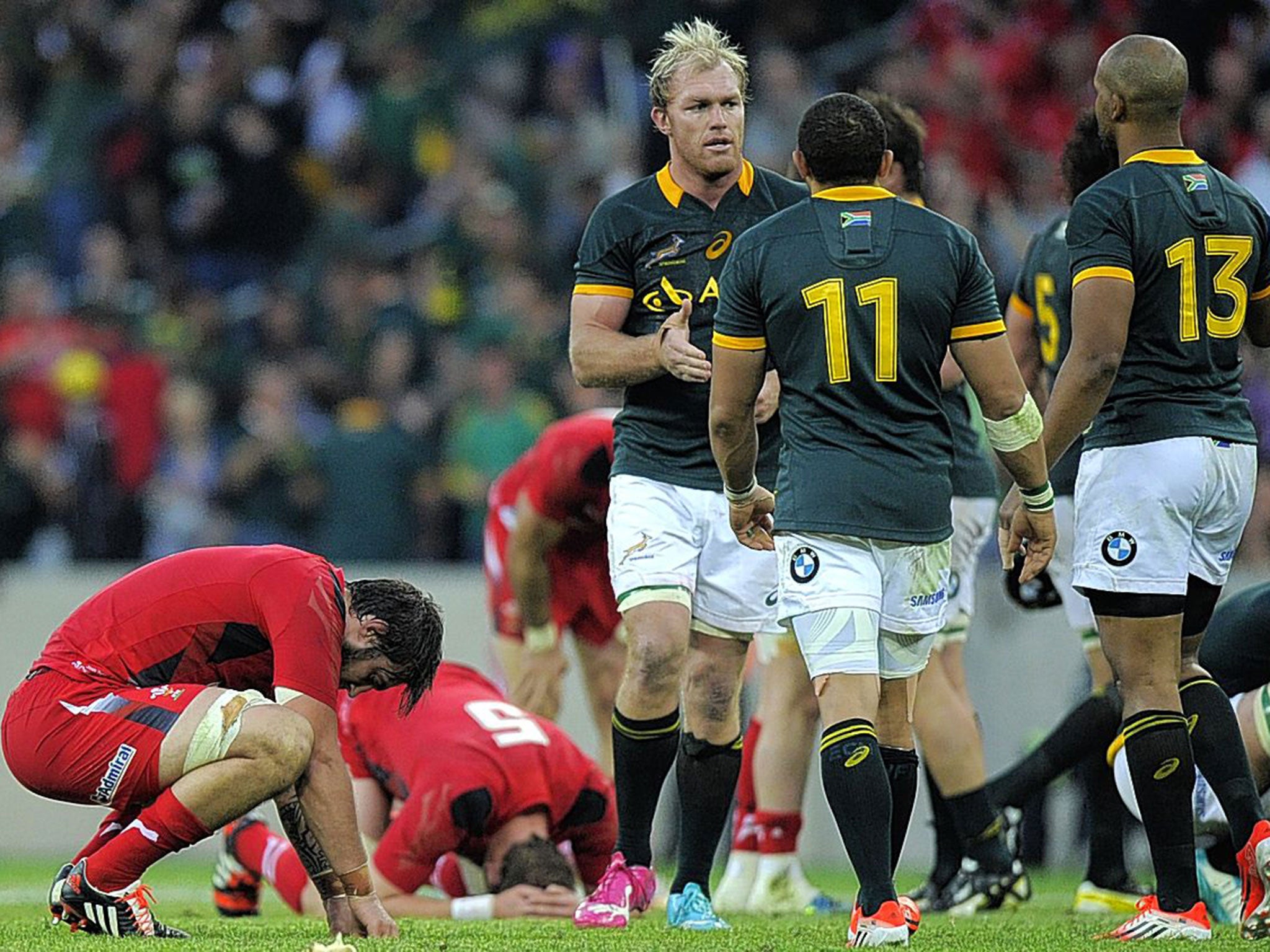 Broken hearts: Wales players are disconsolate as the Springboks celebrate their victory at the final whistle