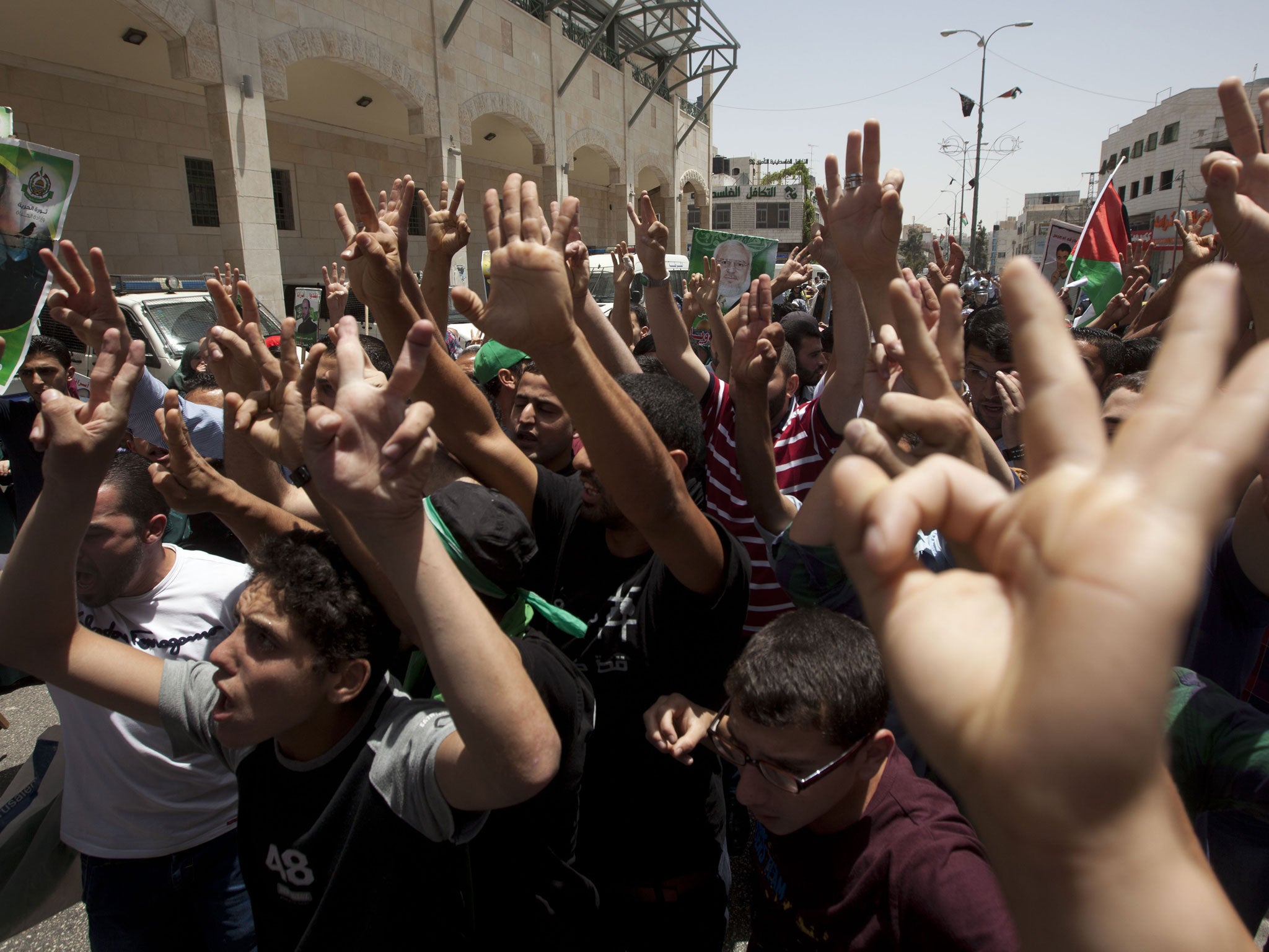 Hamas supporters signal support for the recent abduction of three Israeli teenagers during a protest in Hebron