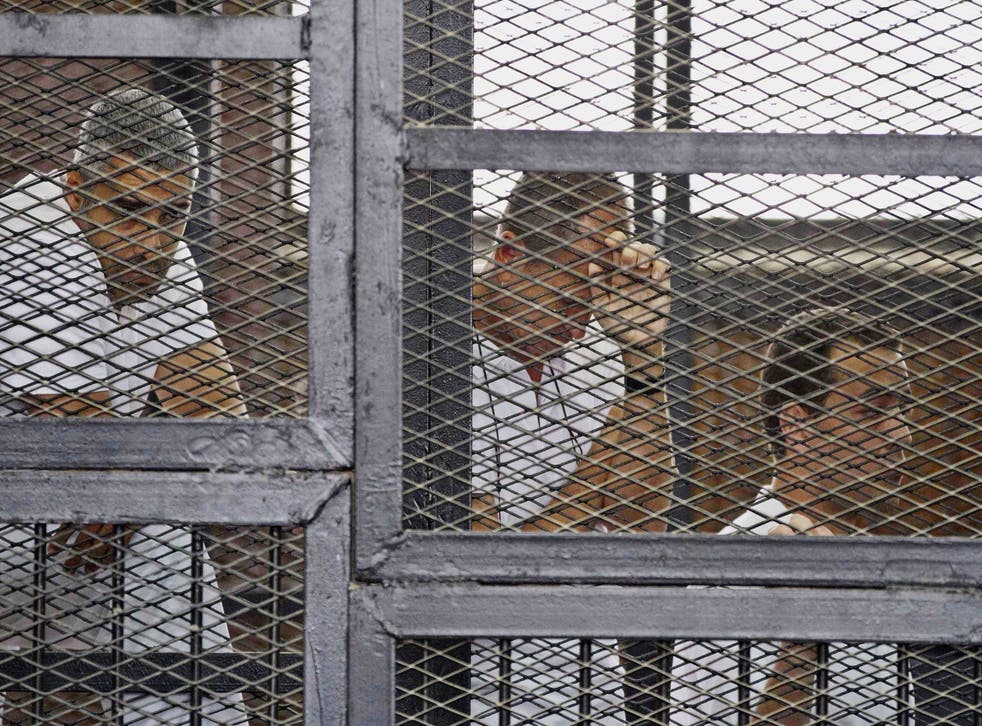 In this Thursday, May 15, 2014 file photo, from left, Mohammed Fahmy, Canadian-Egyptian acting bureau chief of Al-Jazeera, Australian correspondent Peter Greste, and Egyptian producer Baher Mohamed appear in a defendant's cage along with several other def