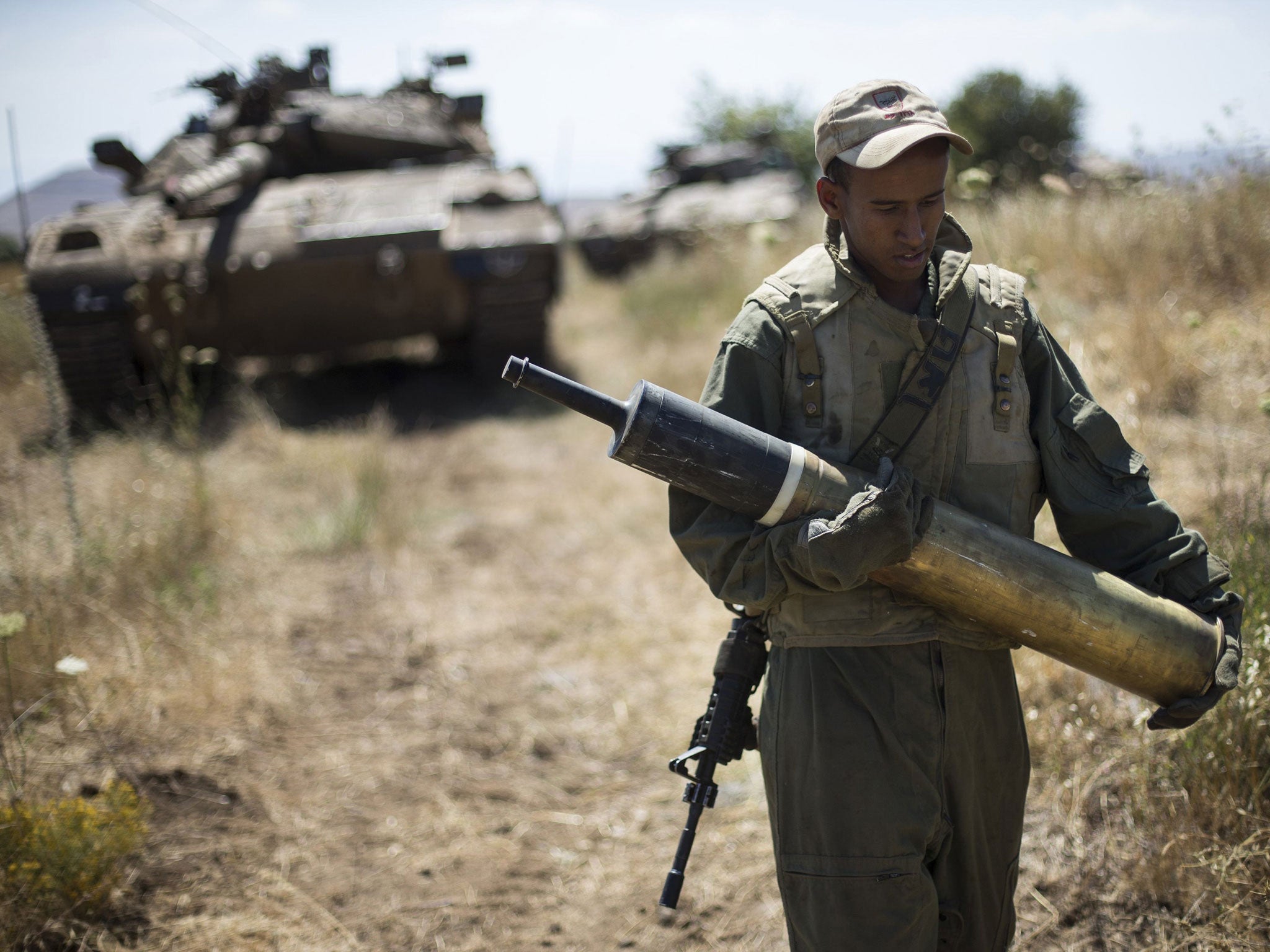 An Israeli soldier carries a tank shell near Alonei Habashan on the Israeli occupied Golan Heights, close to the ceasefire line between Israel and Syria June 22, 2014
