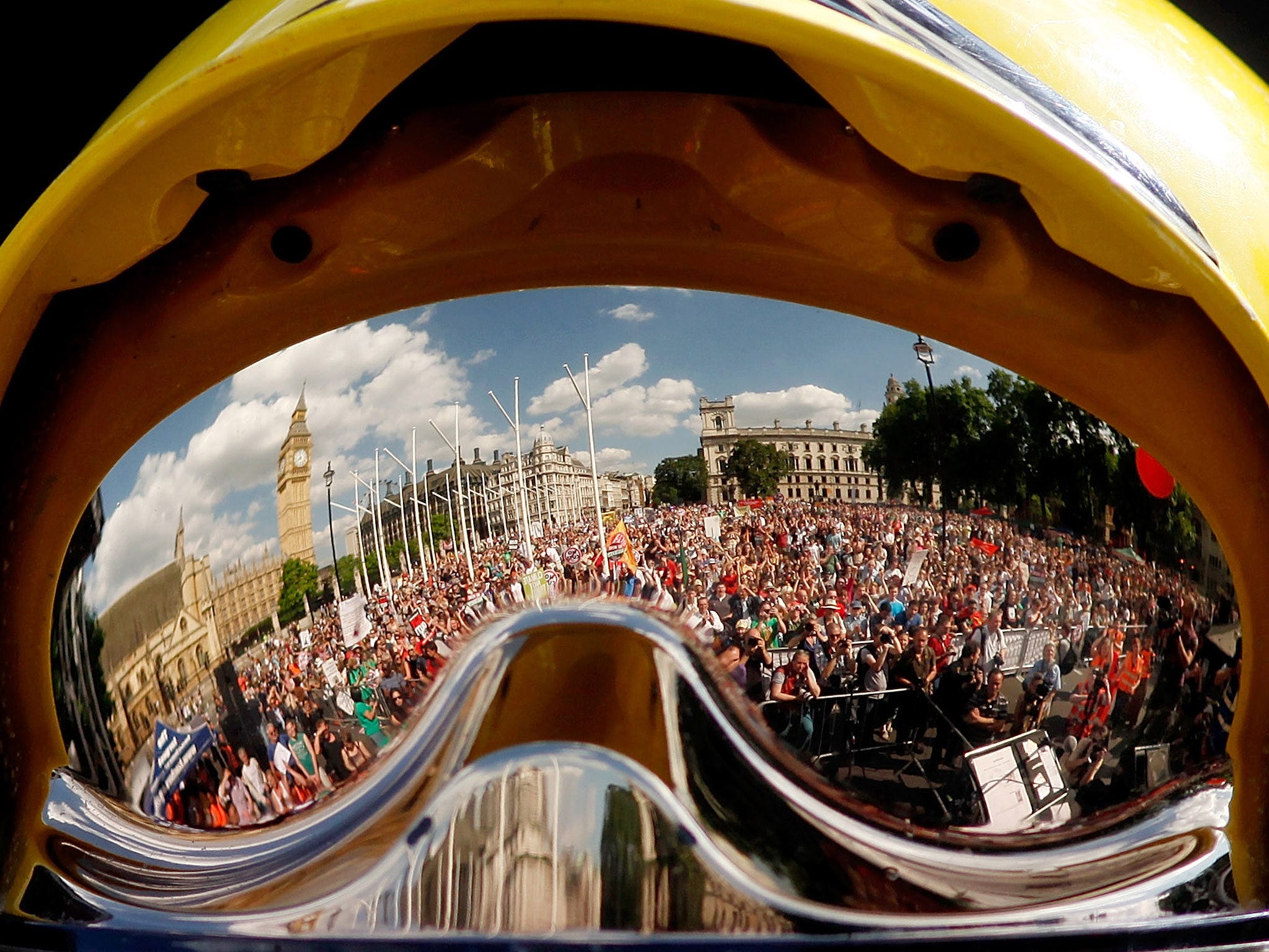 A crowd of thousands of demonstrators are reflected in a firefighter's helmet held up on stage in front of the gathering in Parliament Square in London. The crowd marched from Oxford Circus to Parliament Square to voice their opposition to government aust