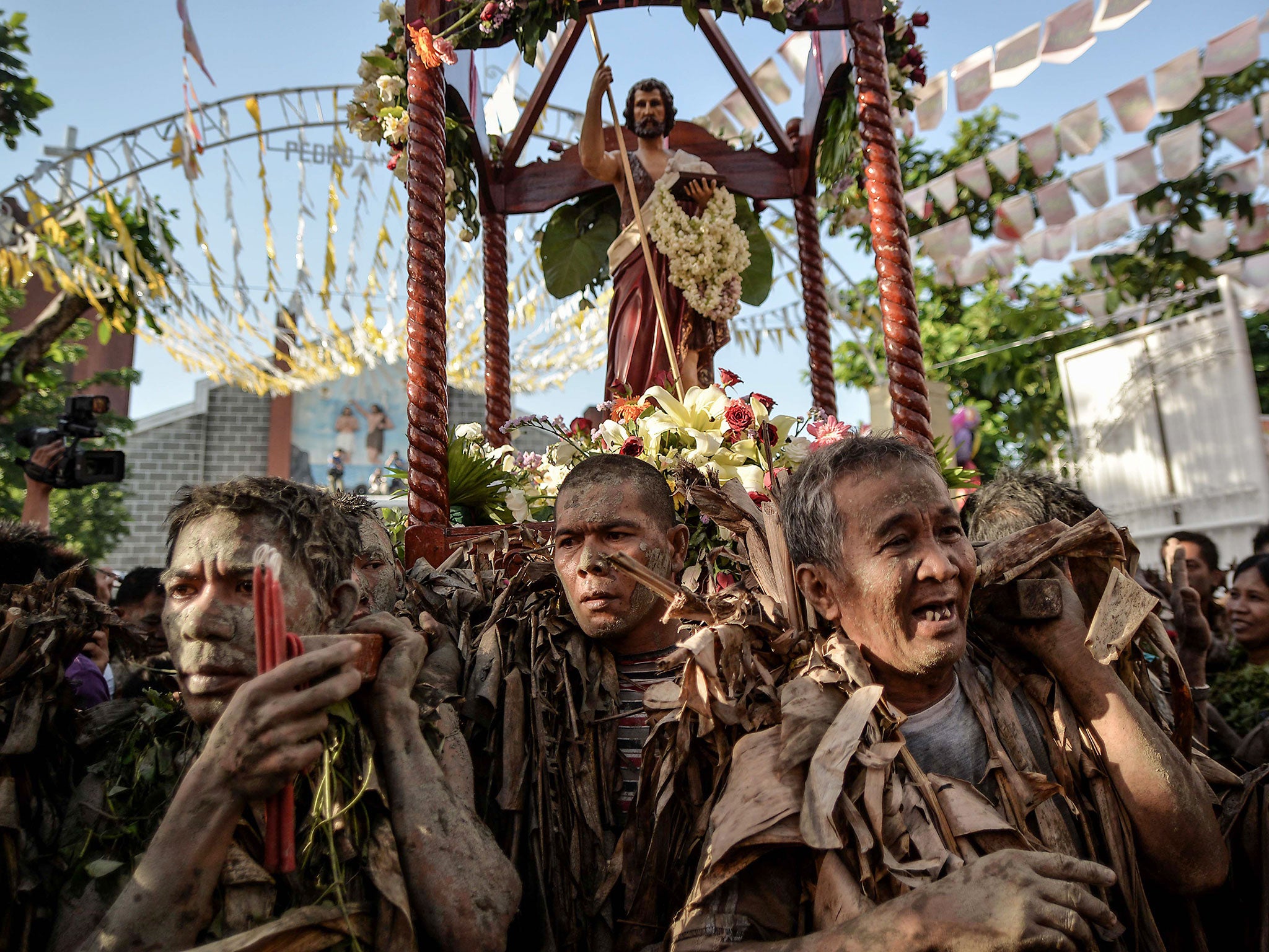 Filipino devotees covered in mud and dried leaves carry an image of Saint John the Baptist during a procession in a pagan religious tradition to mark the 'Taong Putik' (Mud People) festival and the Feast of Saint John the Baptist in the village of Bibicla