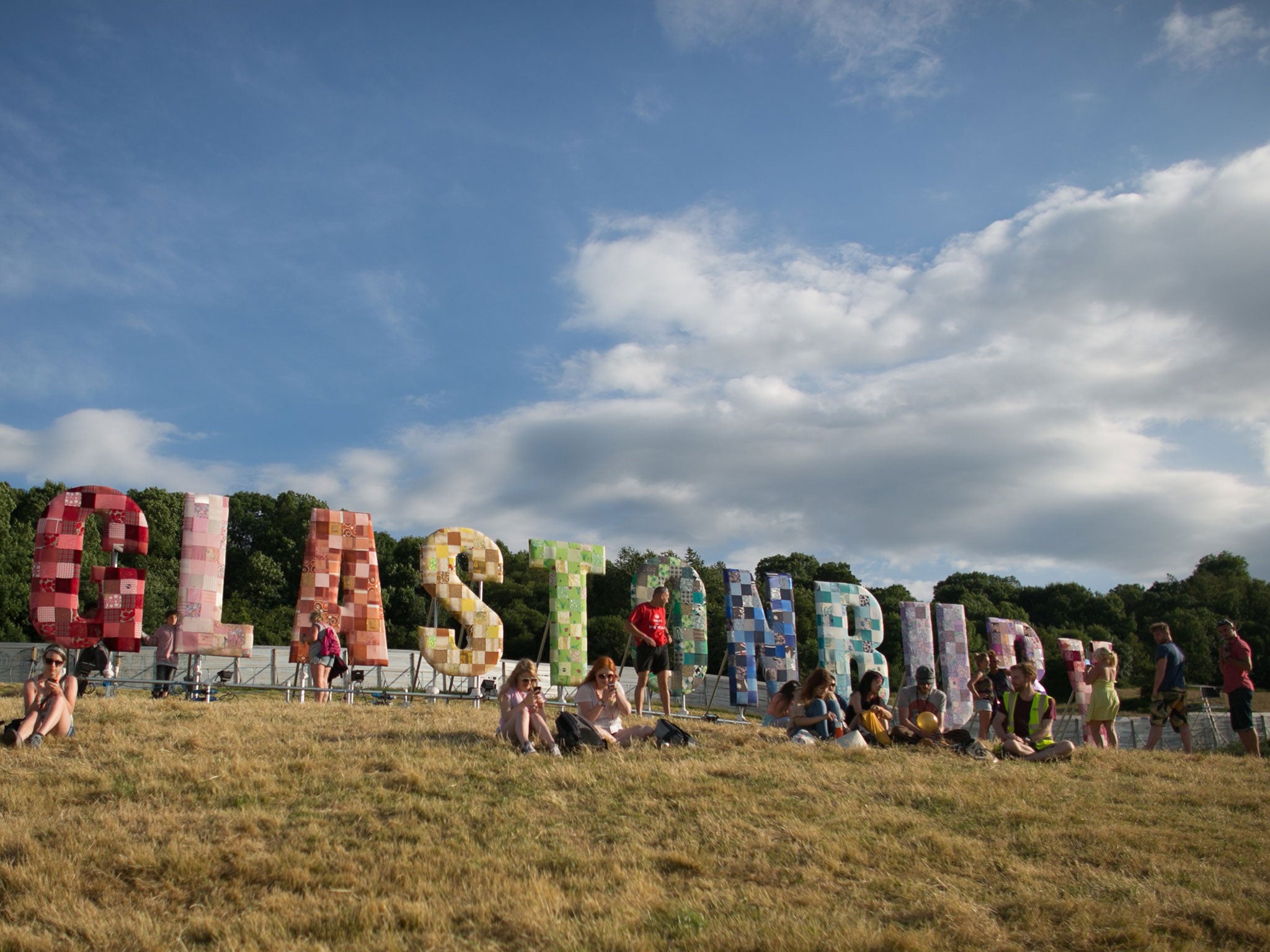 People gather below the Glastonbury sign at Worthy Farm in Pilton on the eve of the first day of the 2014 Glastonbury Festival