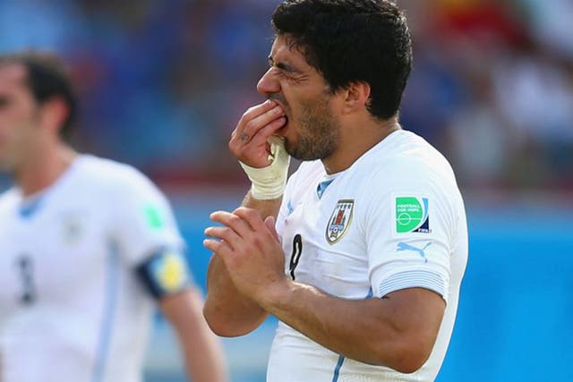 Luis Suarez holds his teeth after biting Giorgio Chiellini