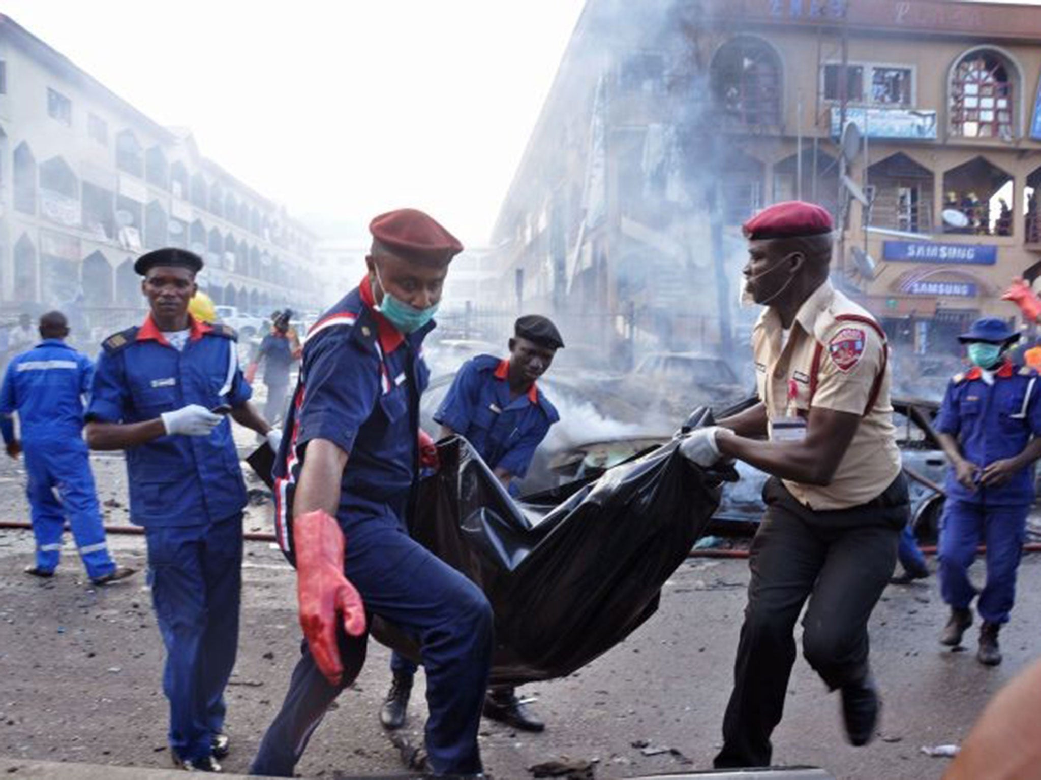 Rescue workers carry the remains of a person in a body bag, after a explosion at a shopping mall in Abuja, Nigeria, Wednesday, June 25,